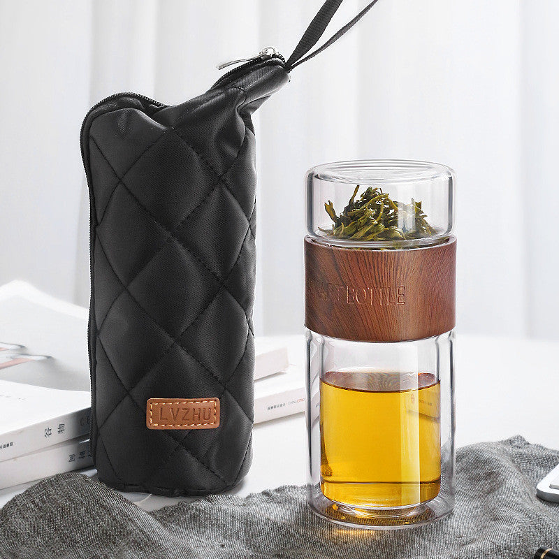 Portable travel drinkware set featuring high borosilicate glass tea tumbler and protective sleeve on a wooden table.