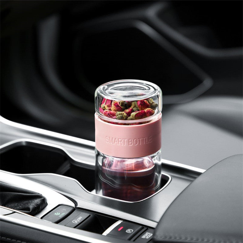 Portable travel drinkware set featuring high borosilicate glass tea tumbler and protective sleeve on a wooden table.