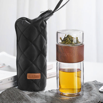 Portable travel drinkware set featuring high borosilicate glass tea tumbler and protective sleeve on a wooden table.