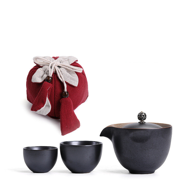 Portable teaware set featuring a teapot and two cups with a red carrying pouch for convenient tea on the go.