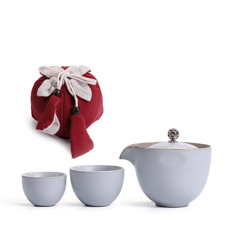 Portable teaware set featuring a teapot and two cups with a red carrying pouch for convenient tea on the go.