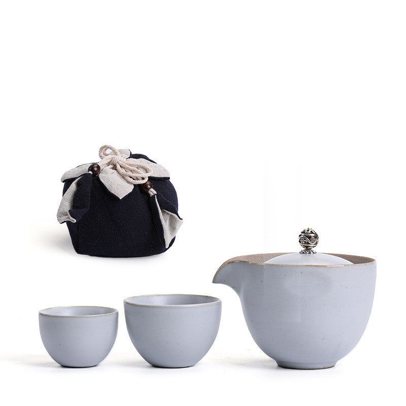 Portable teaware set featuring a teapot and two cups with a red carrying pouch for convenient tea on the go.