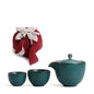 Portable teaware set featuring a teapot and two cups with a red carrying pouch for convenient tea on the go.