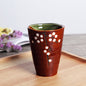 Japanese ceramic mug featuring a delicate flower pattern and elegant round shape on a wooden surface.