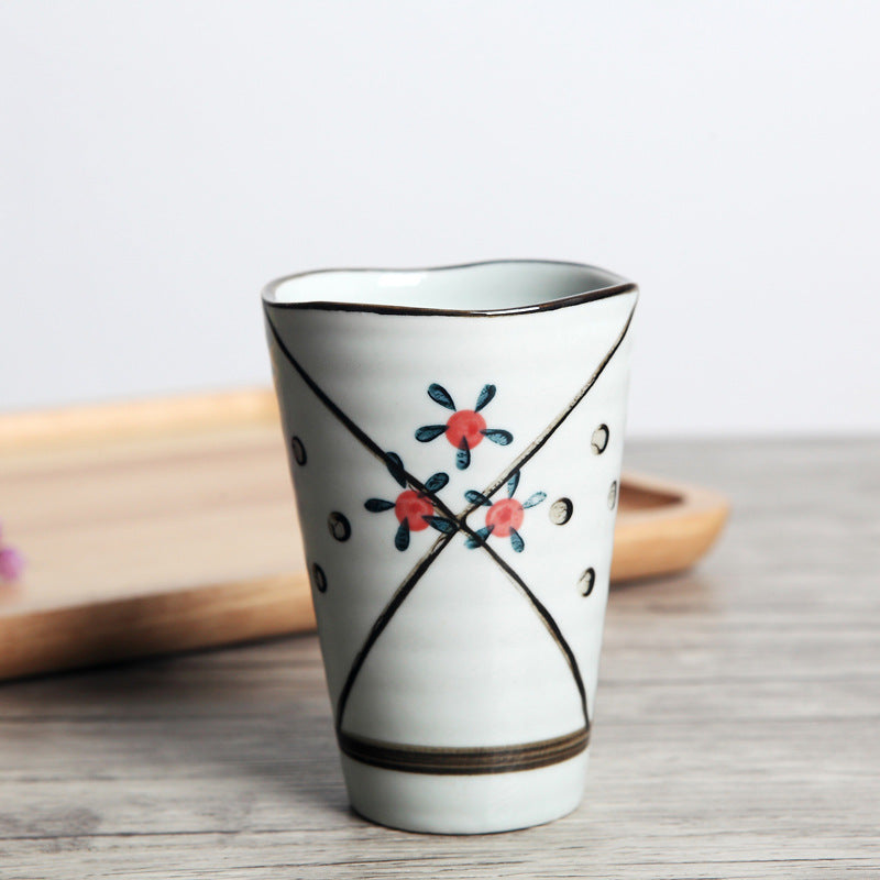Japanese ceramic mug featuring a delicate flower pattern and elegant round shape on a wooden surface.