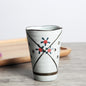 Japanese ceramic mug featuring a delicate flower pattern and elegant round shape on a wooden surface.