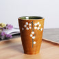 Japanese ceramic mug featuring a delicate flower pattern and elegant round shape on a wooden surface.
