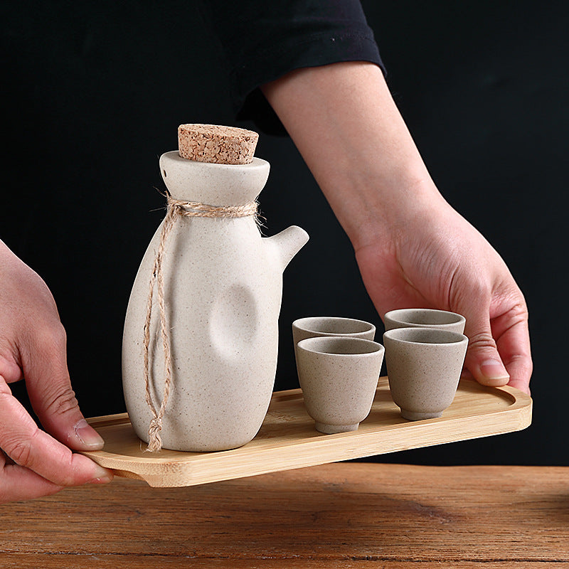 Japanese sake pot set displayed on a bamboo tray with four ceramic cups, perfect for traditional drinkware.