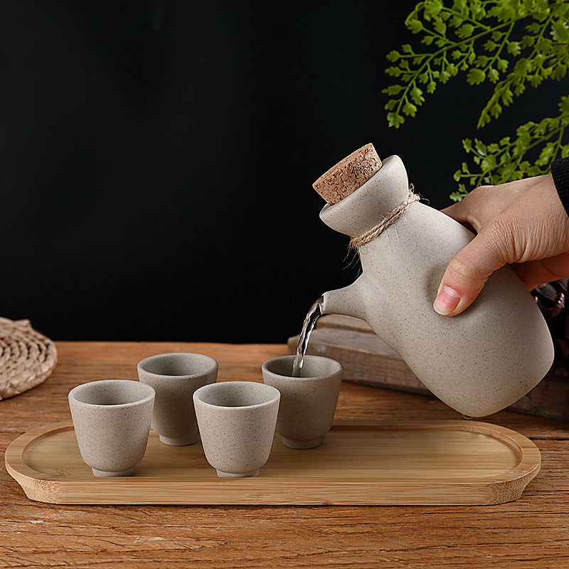 Japanese sake pot set displayed on a bamboo tray with four ceramic cups, perfect for traditional drinkware.