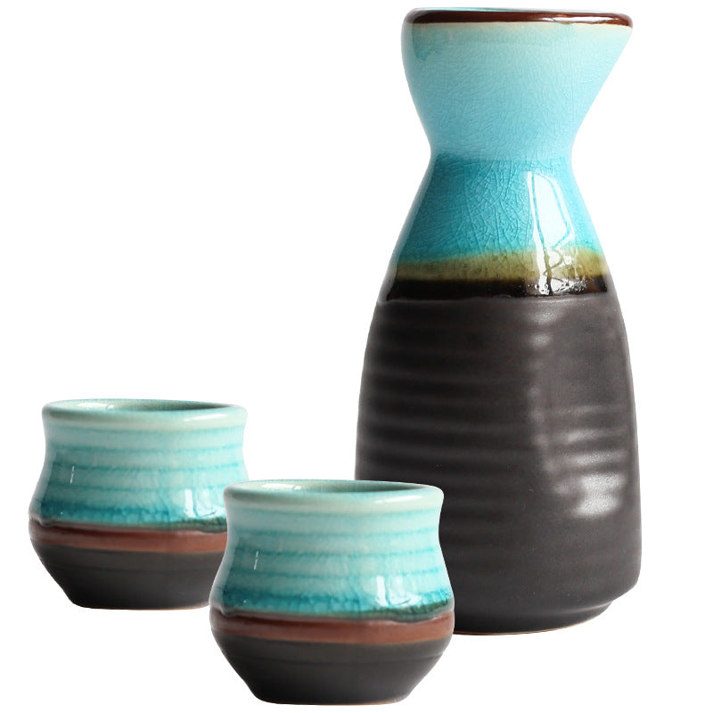 Pouring Japanese sake from a pot into two cups on a blue plate, showcasing Japanese sake pot elegance.