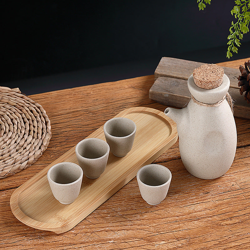 Japanese sake pot set displayed on a bamboo tray with four ceramic cups, perfect for traditional drinkware.