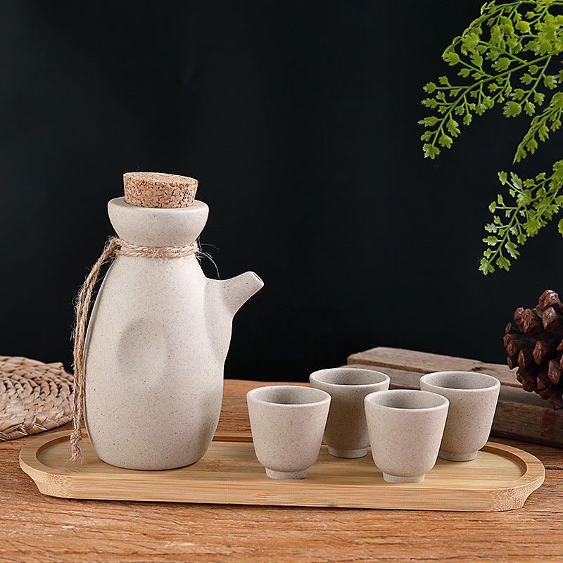 Japanese sake pot set displayed on a bamboo tray with four ceramic cups, perfect for traditional drinkware.