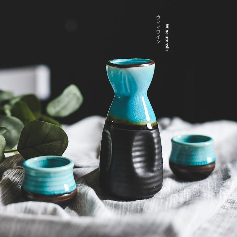 Pouring Japanese sake from a pot into two cups on a blue plate, showcasing Japanese sake pot elegance.